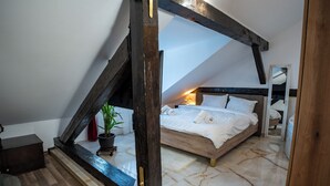 A bedroom with a sloped ceiling, a bed, a nightstand, a potted plant, and a mirror. - Barrique Milescu 5 (Brașov)