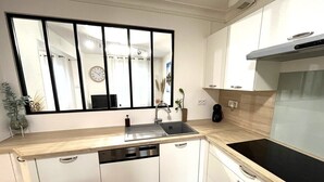 Una cucina moderna con lavastoviglie, lavello, piano cottura e un grande specchio sopra il bancone.