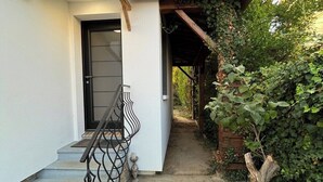 Una casa con esterno bianco, una porta nera e un vialetto in cemento che conduce a un portico in legno.