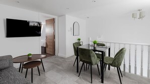 Un comedor moderno con una mesa, sillas y un televisor en la pared.