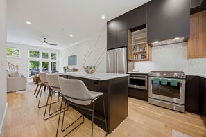 Cozinha moderna com ilha central, eletrodomésticos de aço inoxidável e vista para a sala de estar.