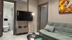 Una sala moderna con un sofá, una mesa de centro, un televisor de pantalla plana y un equipo de aire acondicionado.