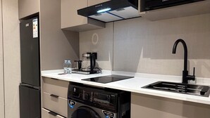 Una cocina moderna con microondas integrado, cafetera, lavavajillas y fregadero.
