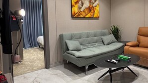 Una sala moderna con un sofá, una mesa de centro, un cuadro y una planta.