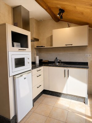 A kitchen with white cabinets, a built-in microwave, and a countertop with a sink. - Casa Rural Prado (San Tirso de Abres)