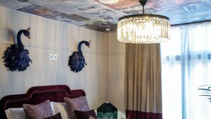 A hotel room with a bed, a chandelier, and a wall with newspaper clippings. - Black Cap Camden (London)