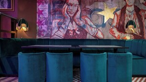 A restaurant with teal seating, a mural on the wall, and a checkered floor. - Black Cap Camden (London)