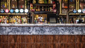 A bar area with a marble countertop, multiple beer taps, and a variety of bottles in the background. - Black Cap Camden (London)