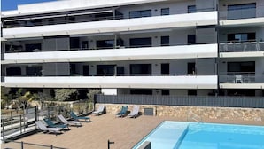Ein mehrstöckiges Hotel mit Poolbereich auf dem Dach, Liegestühlen und einem klaren, blauen Pool.