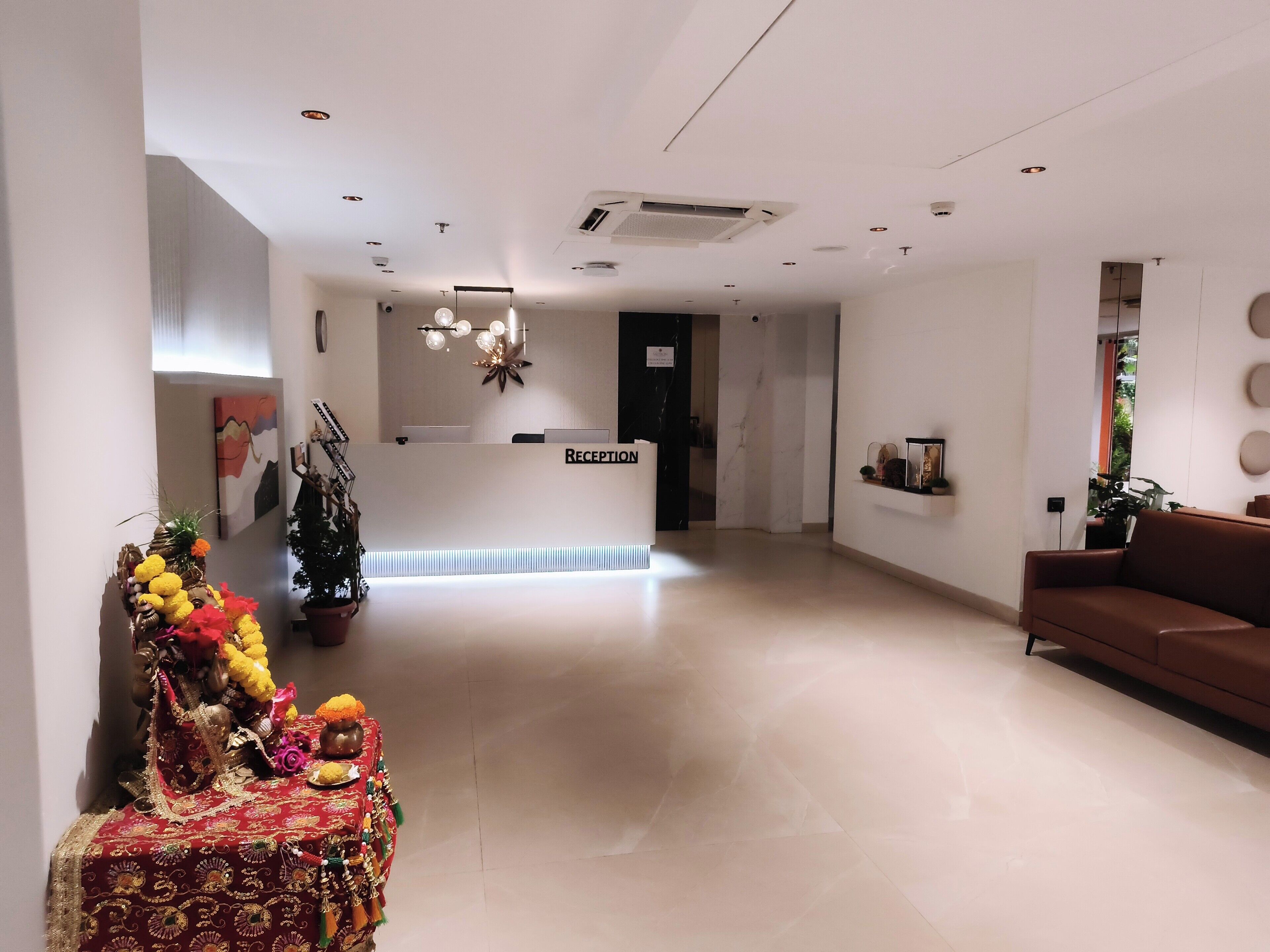 A hotel reception area with a reception desk, a sofa, and a decorative altar.