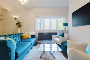 A modern living room with a blue sofa, a white armchair, and a glass coffee table. - Stunning 3BDR Retreat Near Tower Bridge (Greater London)