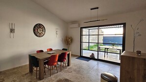 Ein Essbereich mit Holztisch und roten Stühlen, einer Wanduhr und einem großen Fenster mit Blick.