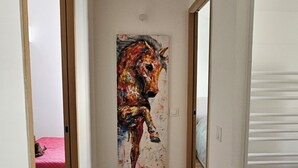 Ein Flur mit Holzboden, einem farbenfrohen Gemälde von einem Pferd an der Wand und Türen zu anderen Räumen.