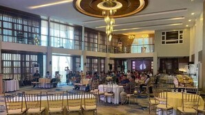 A spacious indoor venue with multiple dining areas, a central chandelier, and a high ceiling. - Casa Familia Hotel (Aurora)