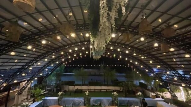 An indoor venue with a high ceiling, hanging plants, and multiple tables and chairs arranged for dining. - Casa Familia Hotel (Aurora)