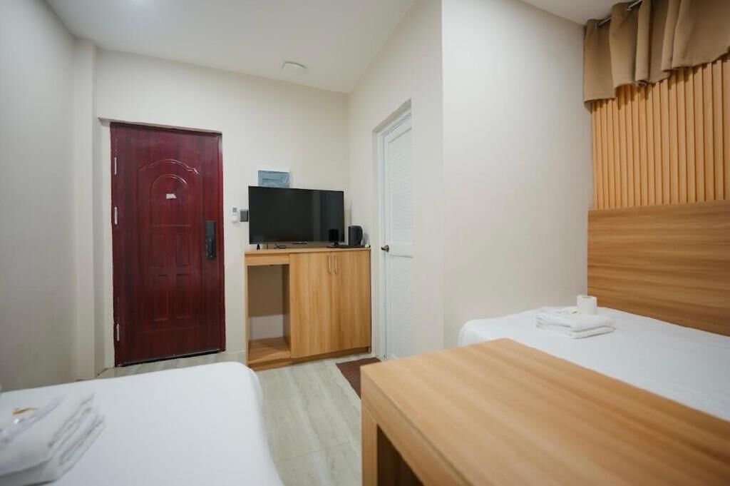 Una habitación de hotel con cama, escritorio con televisor, armario y puerta.