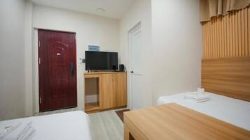 Una habitación de hotel con cama, escritorio con televisor, armario y puerta.