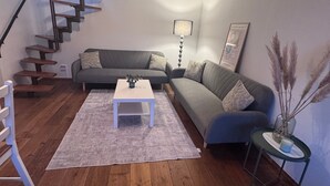 Un salon moderne avec un escalier en bois, un canapé gris, une table basse blanche et une lampe.