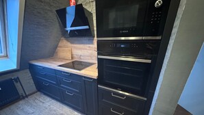 Une cuisine équipée d’un four Bosch, d’un micro-ondes encastré et d’un plan de travail en bois.