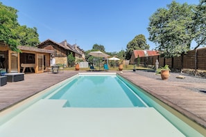 Piscina rectangular con muelle de madera, rodeada de casas y árboles.