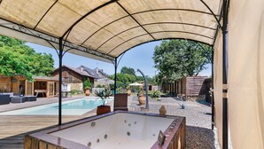 A wooden deck with a hot tub, a pool, and a covered area with a view of houses and trees. - Gîte "Le Four à Pain" – Charming Studio with Private Terrace in Périgord Noir (Paulin)