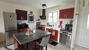 Una cocina moderna con una isla central, electrodomésticos de acero inoxidable y armarios rojos.