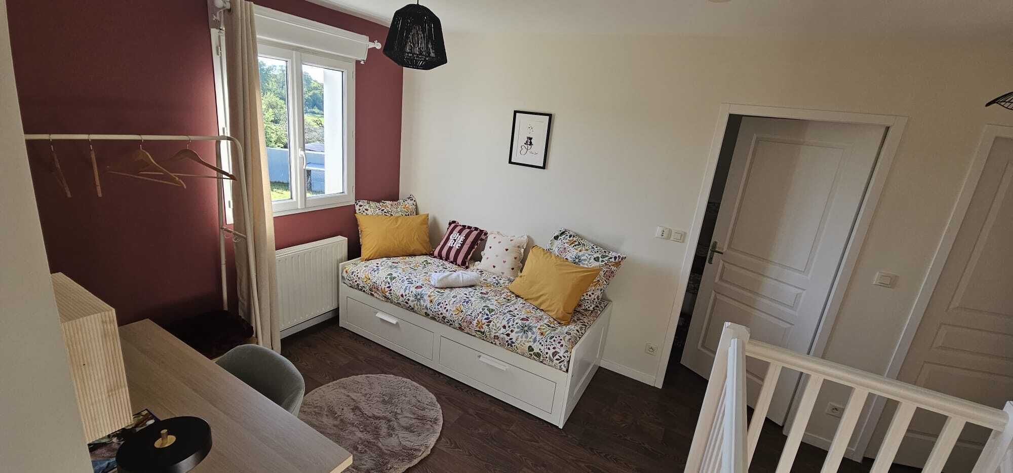 A small, cozy room with a bed, a window, a door, and a radiator.