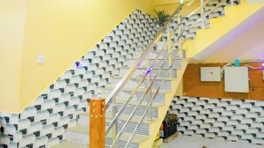 A staircase with a patterned wall, a handrail, and a ceiling light fixture. - HOTEL SIYARAM ASHRAY (Faizabad)