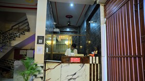 A reception desk with a marble top, a potted plant, and a staircase in the background. - HOTEL SIYARAM ASHRAY (Faizabad)