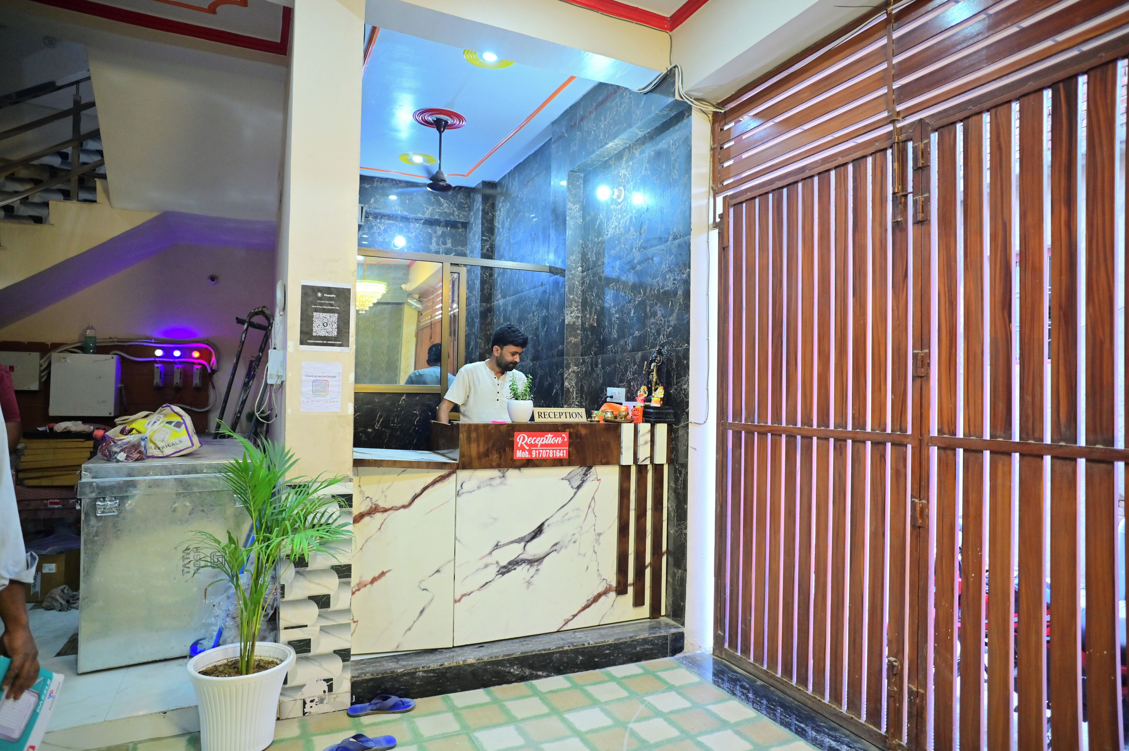 A reception desk with a marble counter, a potted plant, and a closed wooden gate.