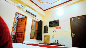 A hotel room with a bed, a TV, an air conditioning unit, a wooden door, and a reception sign. - HOTEL SIYARAM ASHRAY (Faizabad)