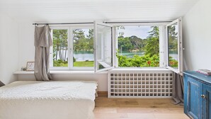 Un dormitorio con cama, una ventana con vista a un lago, un radiador y un armario azul.