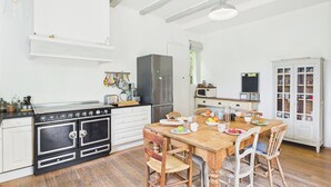 Una cocina con una mesa de madera, sillas, una estufa y un refrigerador.