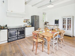 Eine Küche mit Holztisch, Stühlen, Herd und Kühlschrank.