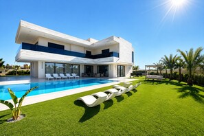 Ein modernes, zweistöckiges Haus mit Swimmingpool, gepflegtem Rasen und einer Pergola.