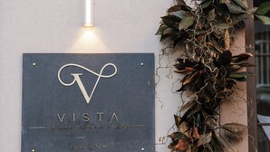 Letrero que dice 'VISTA Bar Aperitif Restaurant Pizzeria' con una planta decorativa a un lado.