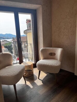 Una habitación con dos sillas, una mesa redonda pequeña y vistas a un paisaje urbano a través de un ventanal grande.
