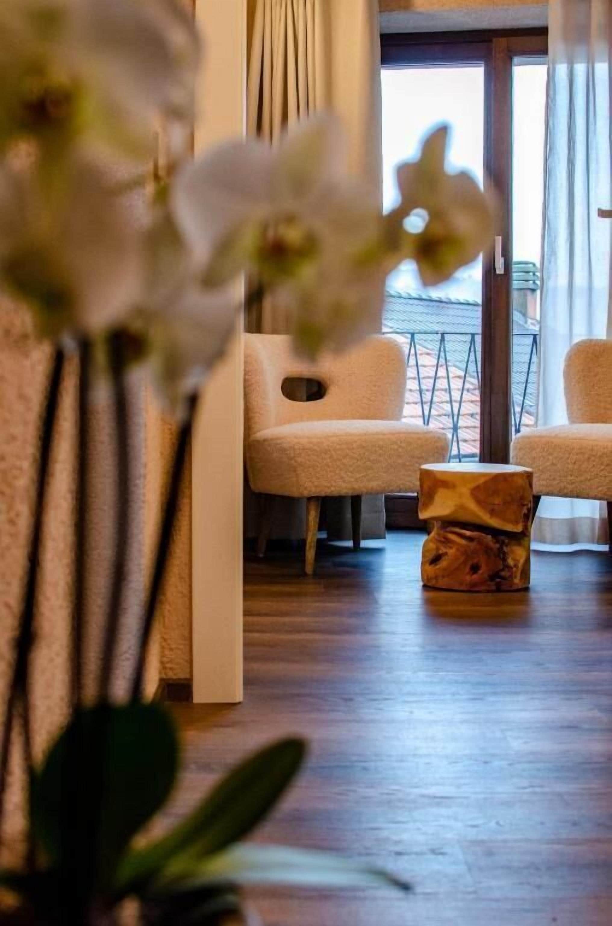 Una habitación con dos sillas, una mesita de madera y vistas a través de una puerta de vidrio.