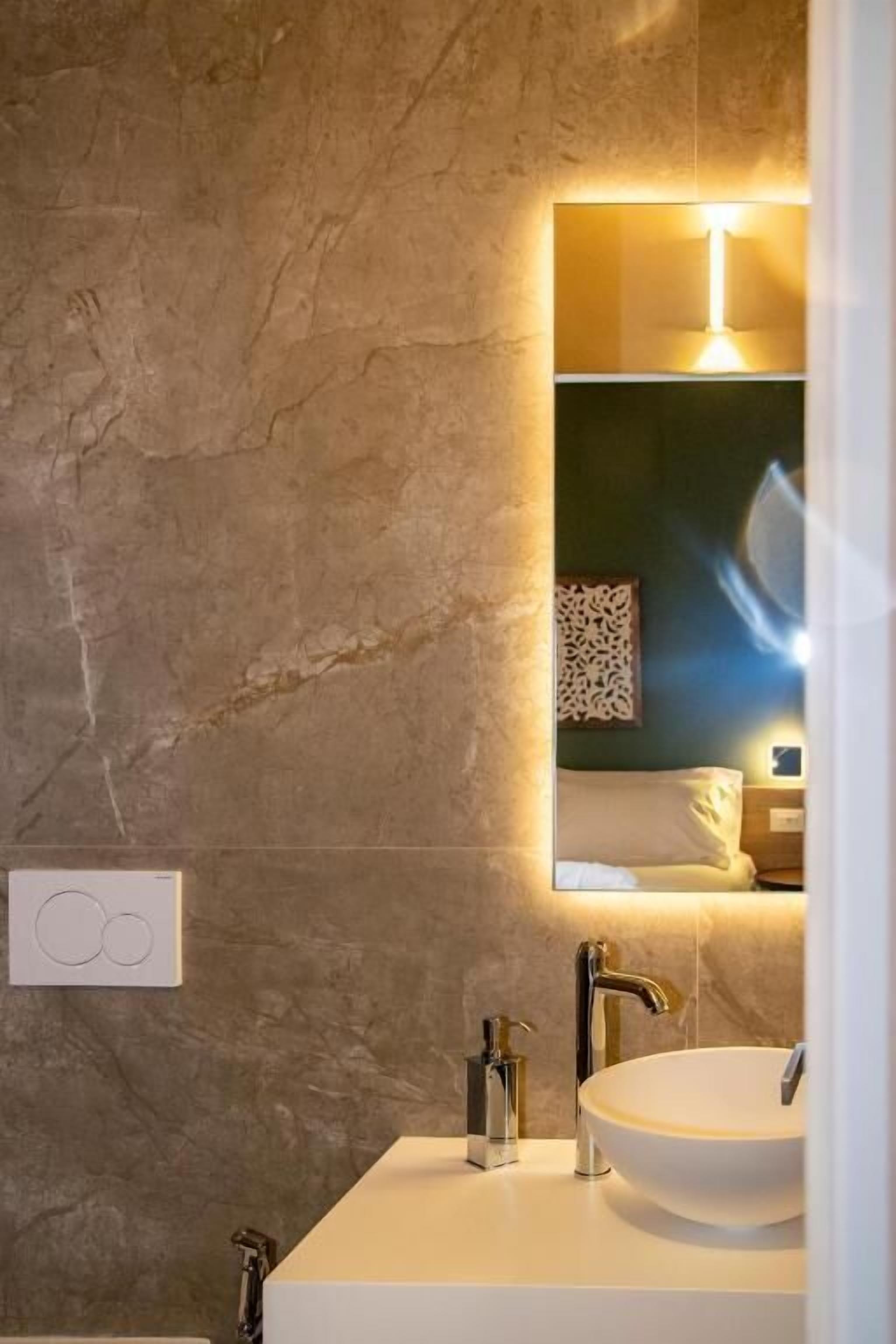Ein Badezimmer mit großem Spiegel, rundem Waschbecken und modernem Design.