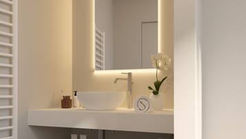 A modern bathroom with a white vanity, a large mirror, and a small potted plant.