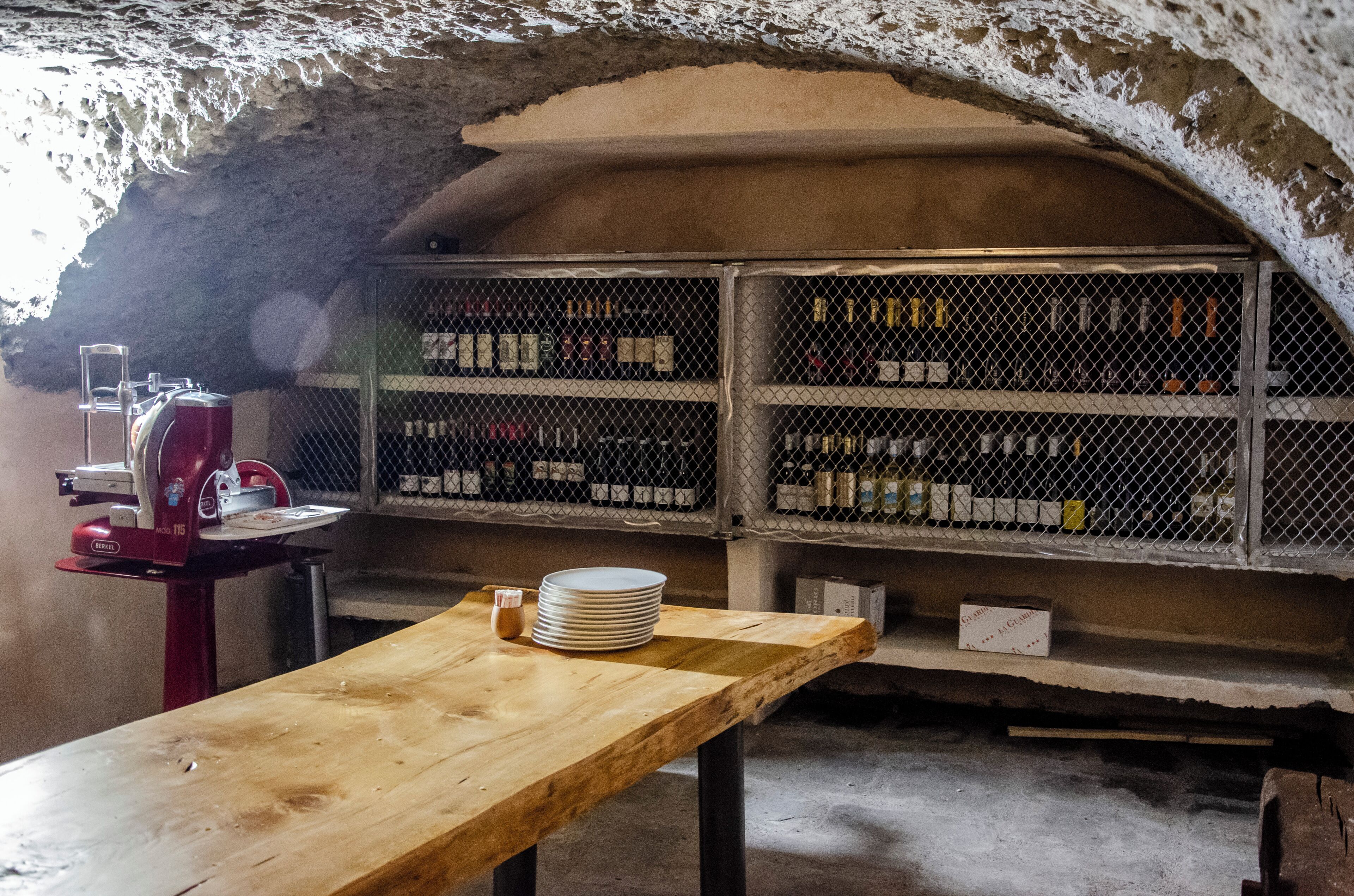 An underground wine cellar with wooden tables, wine racks, and a red wine press.