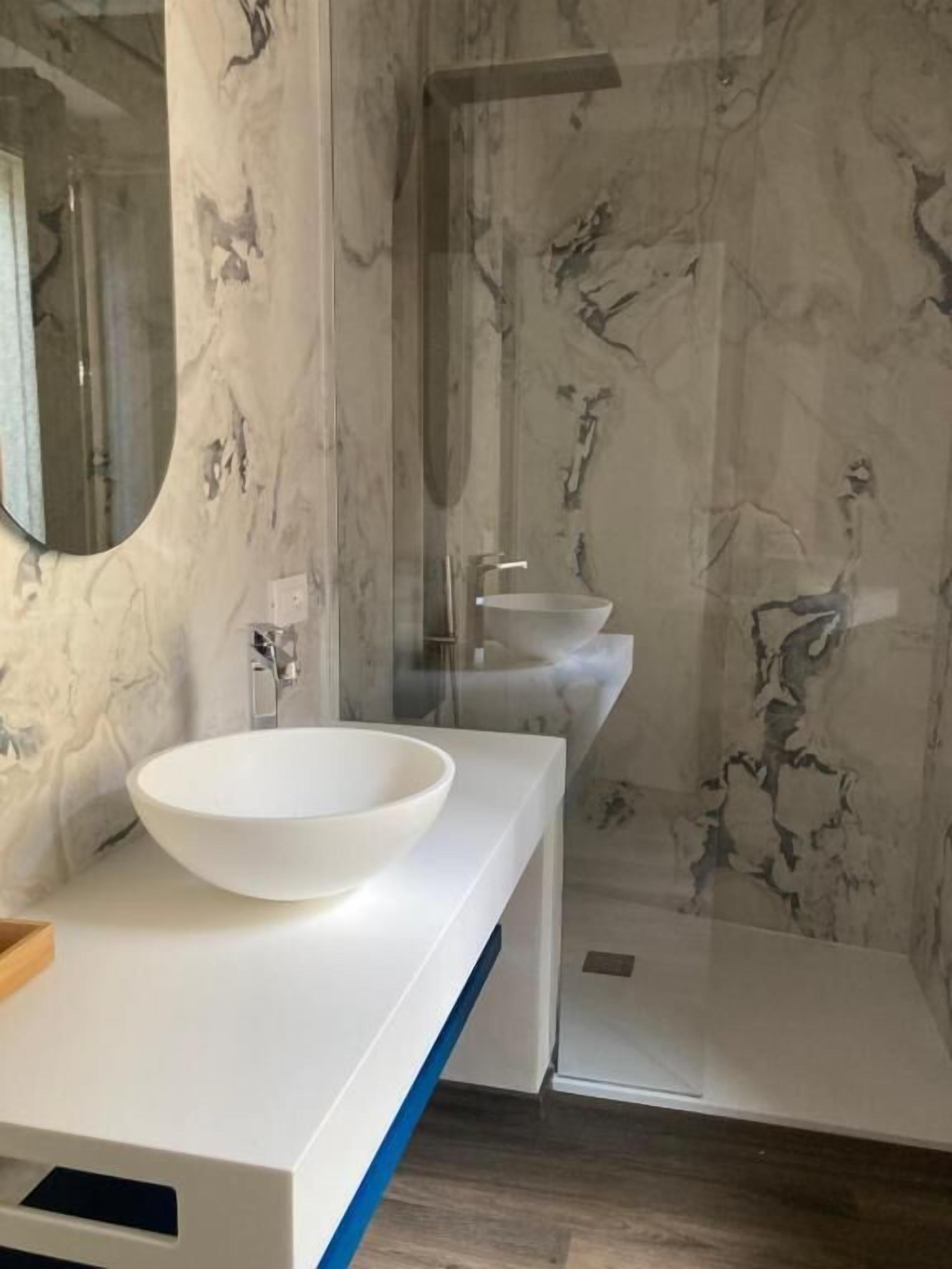 Ein Badezimmer mit einem weißen Waschbecken, einem Spiegel und einer Dusche.
