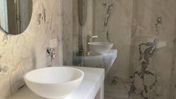 Ein Badezimmer mit einem weißen Waschbecken, einem Spiegel und einer Dusche.
