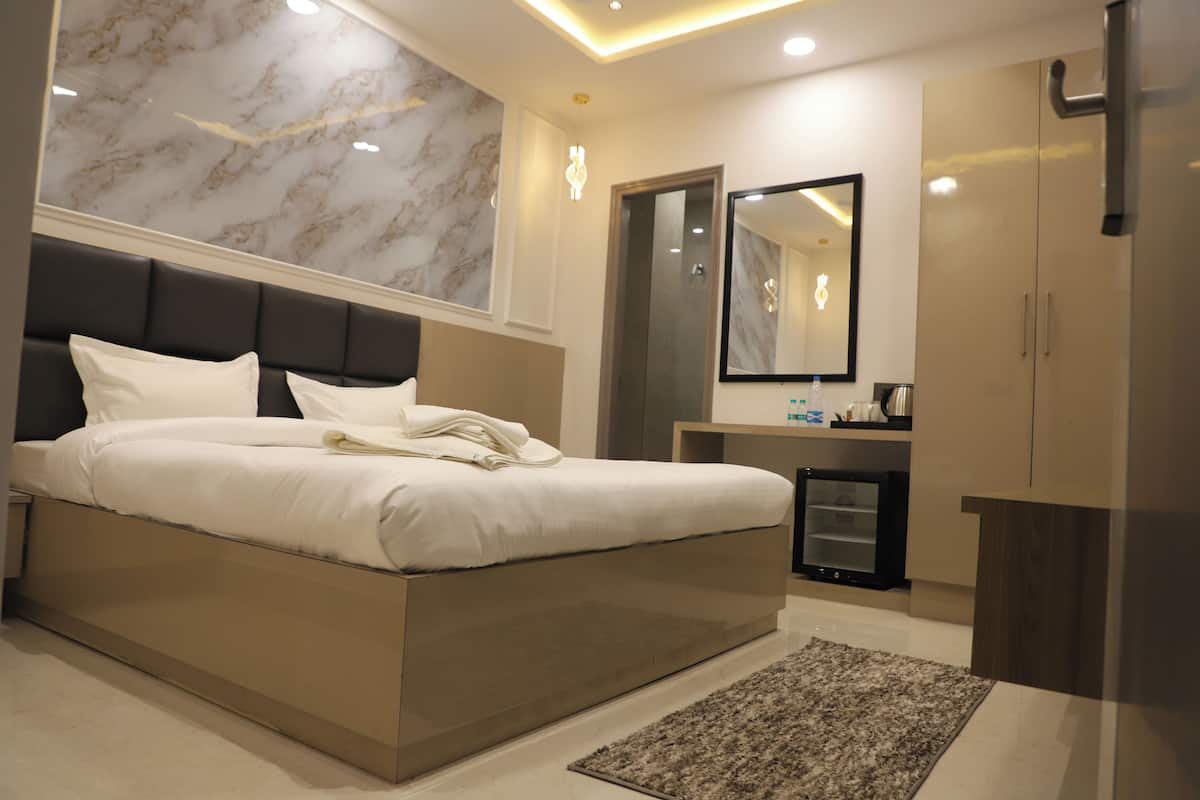 A modern bedroom with a large bed, a bedside table, a mirror, and a wardrobe.