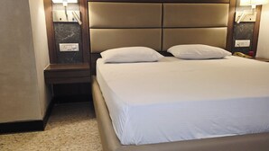 Une chambre d’hôtel avec un grand lit, deux tables de chevet et deux lampes fixées au mur.