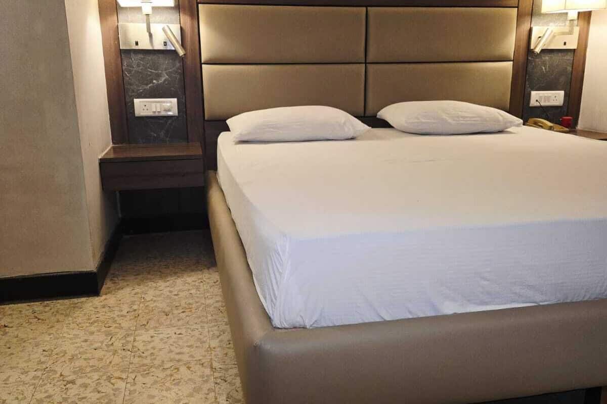 A hotel room with a large bed, two bedside tables, and wall-mounted lamps.