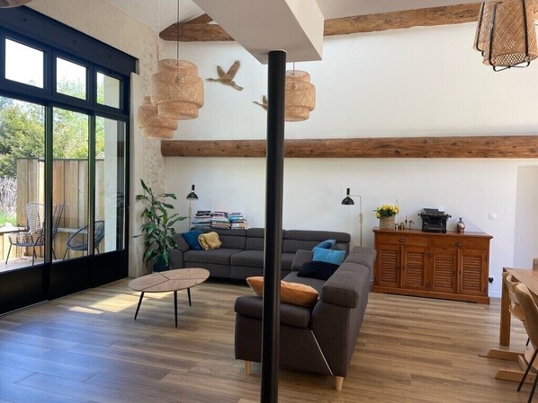A modern living room with a sofa, a coffee table, and a dining area. - Renovated 17th-century wine storehouse, 4 km from Bordeaux-Lacanau cycle path. (Le Taillan-Médoc)