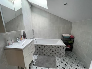 A small bathroom with a white sink, mirror, and bathtub. - Renovated 17th-century wine storehouse, 4 km from Bordeaux-Lacanau cycle path. (Le Taillan-Médoc)