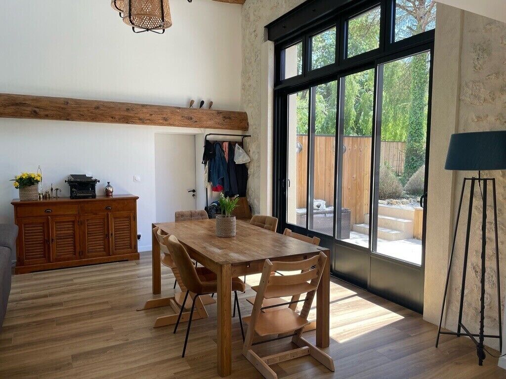 Un comedor con una mesa y sillas de madera, un aparador de madera y un ventanal con vistas a zonas verdes.