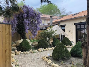 A house with a garden, a wooden fence, and a pergola with purple flowers. - Renovated 17th-century wine storehouse, 4 km from Bordeaux-Lacanau cycle path. (Le Taillan-Médoc)